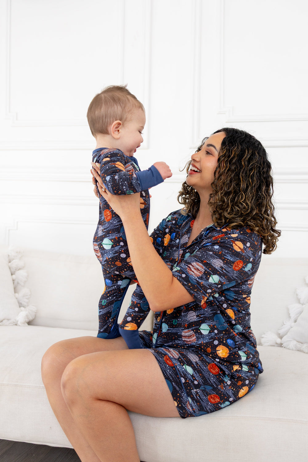 Mom on a couch lifting her baby, both in the Planetarium print
