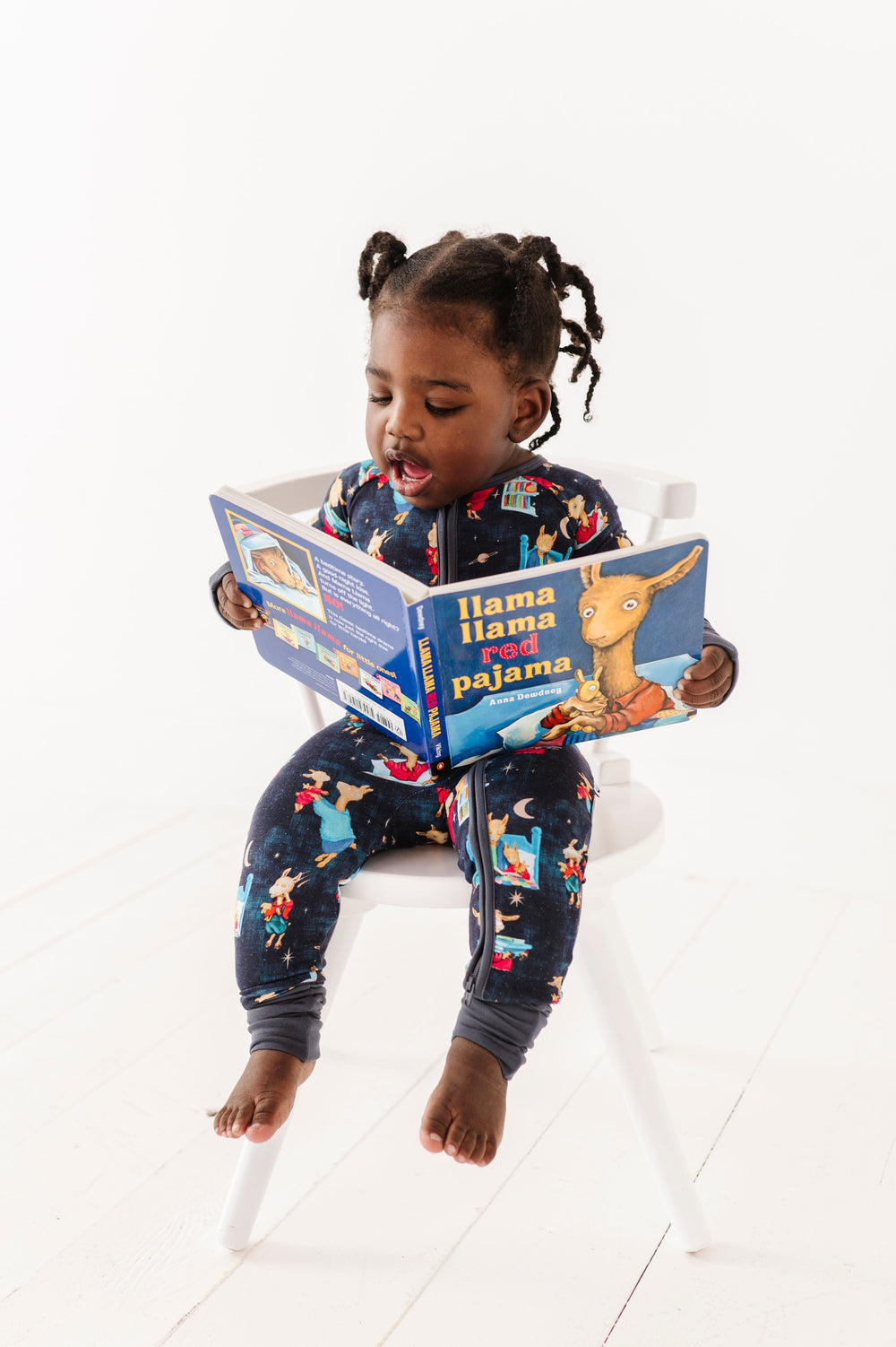 Toddler reading the book in the Llama Llama Red Pajama™ Zip Romper