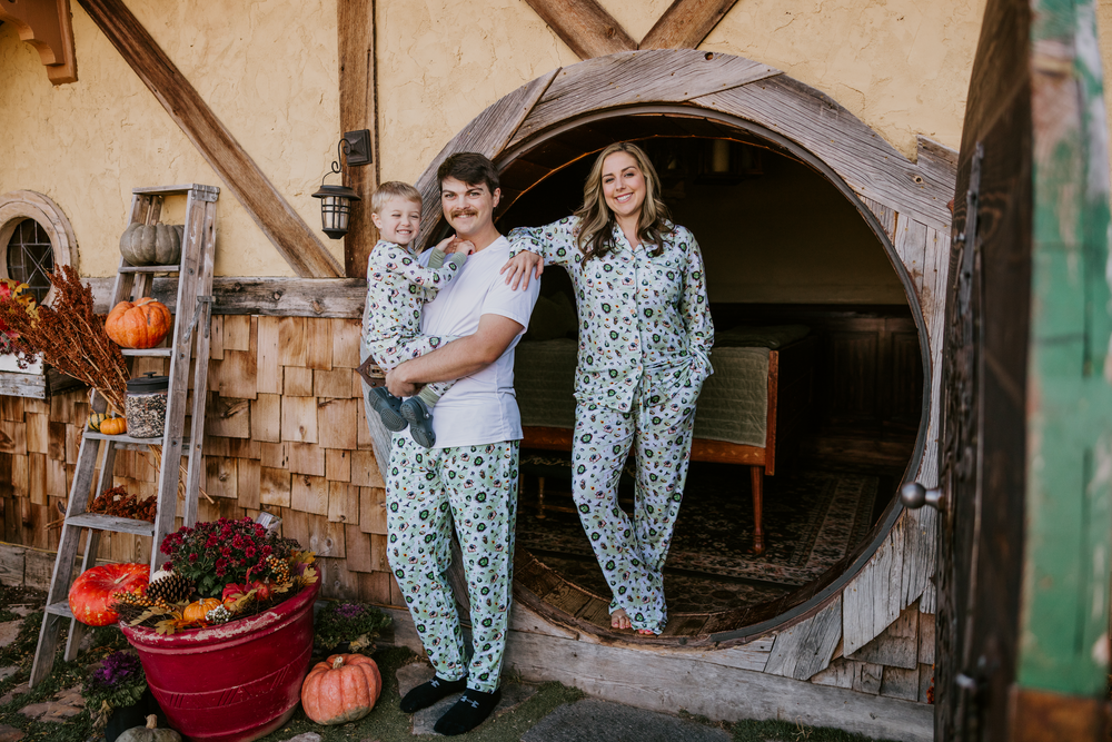 Family in matching The Lord of the Rings™ pajamas at a round Hobbit™ door