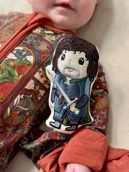 Close-up of the embroidered Aragorn lovey showing stitched cloak, sword and boots