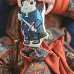 Baby holding the embroidered Aragorn lovey, knotted corner tied, over the matching Lord of the Rings Stained Glass zip romper