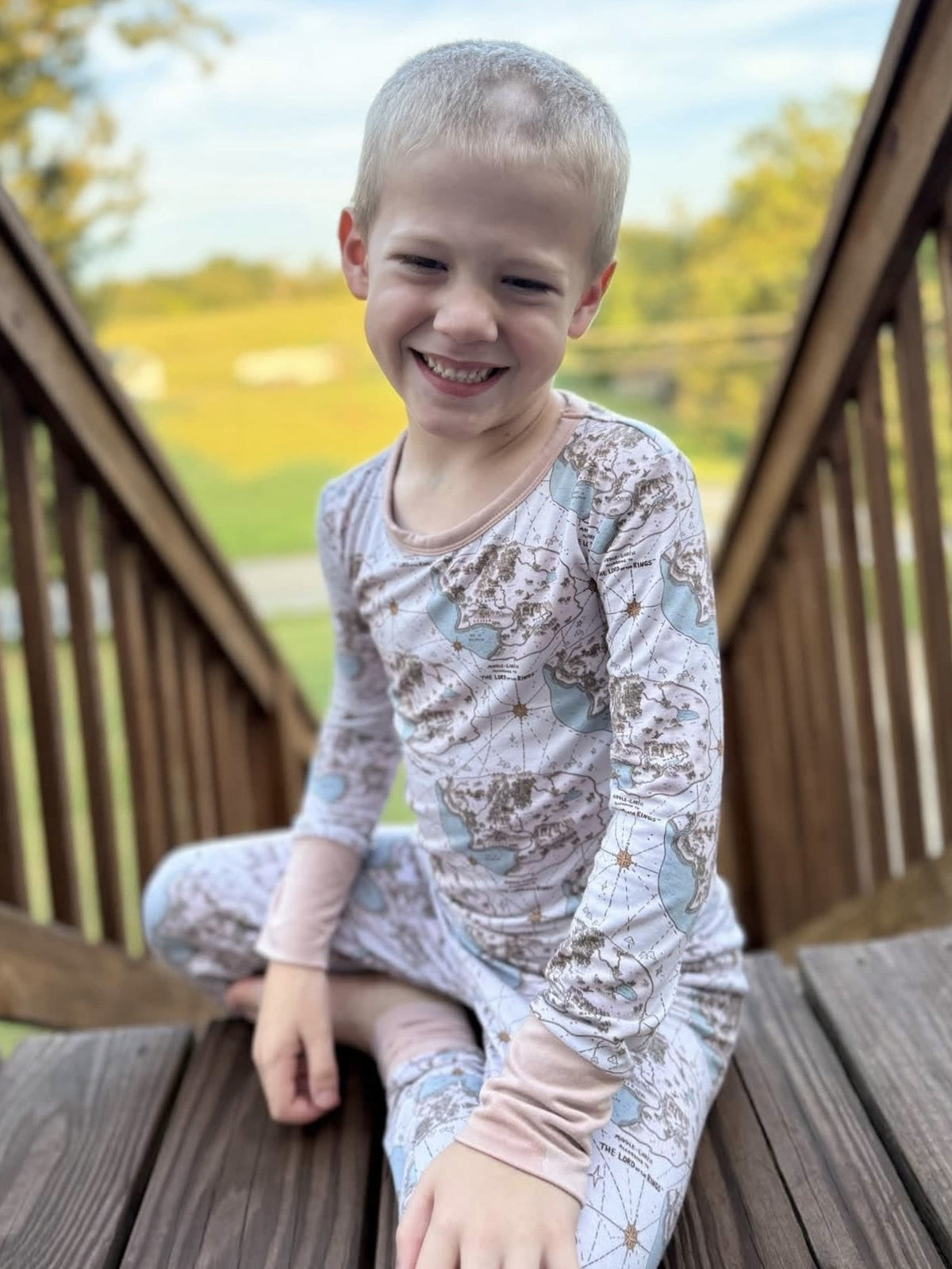 Boy sitting on a wooden bridge in the Tiny Maps LOTR two-piece pajama set